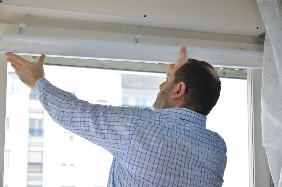 A man installing blinds on a glass window